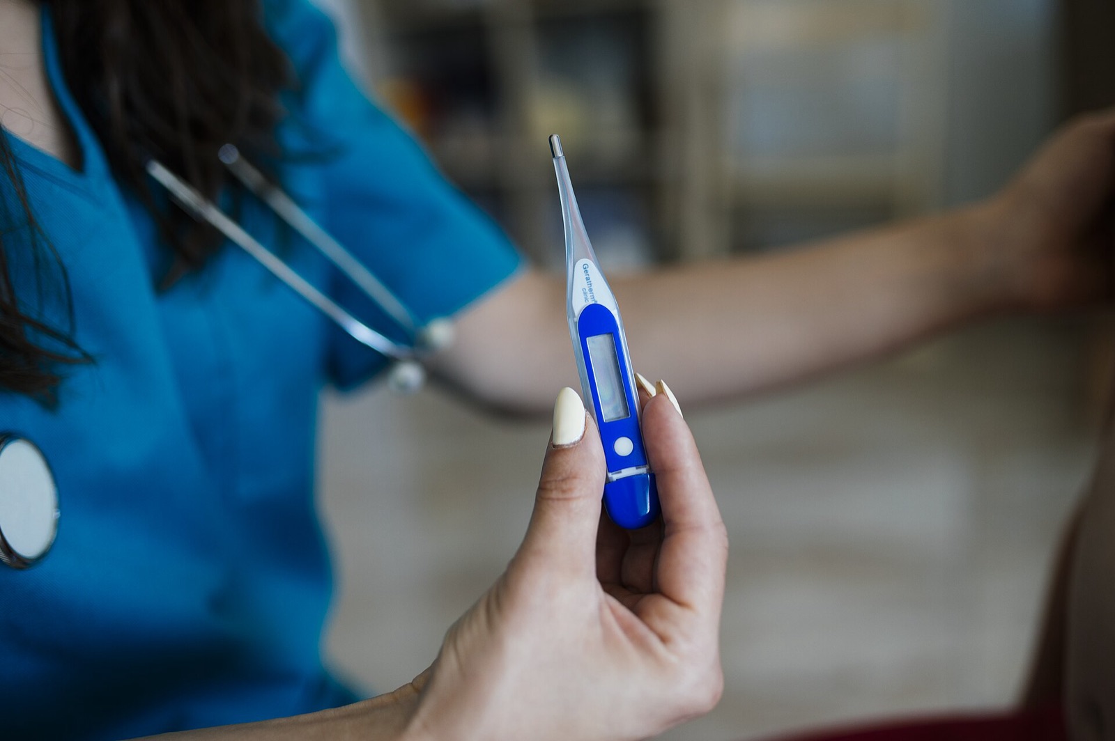 A nurse holds a digital thermometer